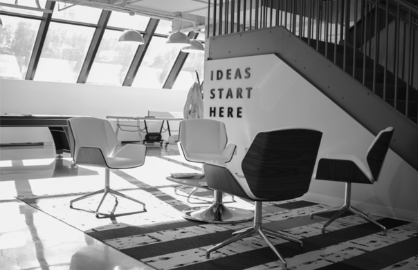 In an empty office, four chairs sit in a square and behind a wall reads “Ideas start here”. They forget “consumer-led”! 