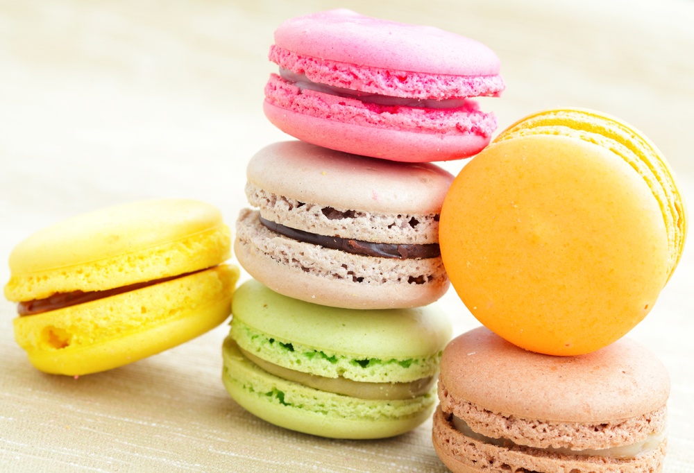 Six macarons, each a different colour, are stacked at varying heights.