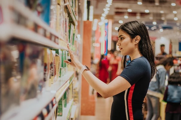 A woman browsing products on a supermarket shelf.