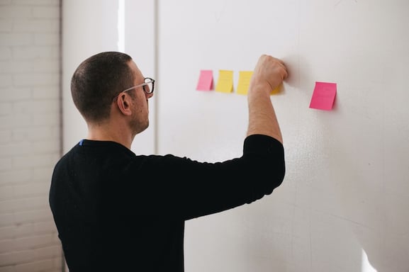 Man applying sticky notes on a wall to outline his product concept