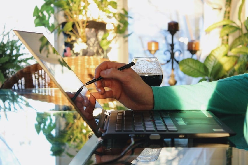 A person touching a stylus to a touch-screen laptop while planning their product concept