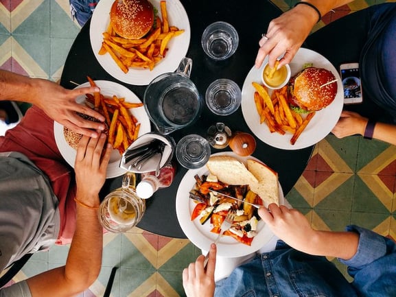 Pre-pandemic: A group of friends eating burgers and salad at a restaurant. 