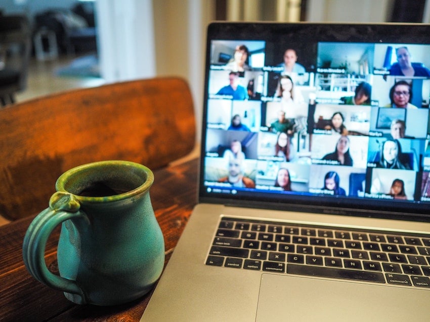 A laptop on a table shows a team on a video call talking about NPD innovation